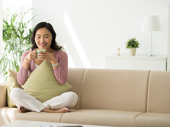 Woman sitting on a sofa enjoying a cup of tea